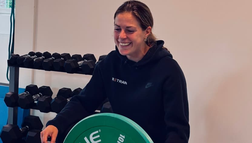 Vrouw in een zwarte trui die met een gewicht werkt in een fitnessruimte