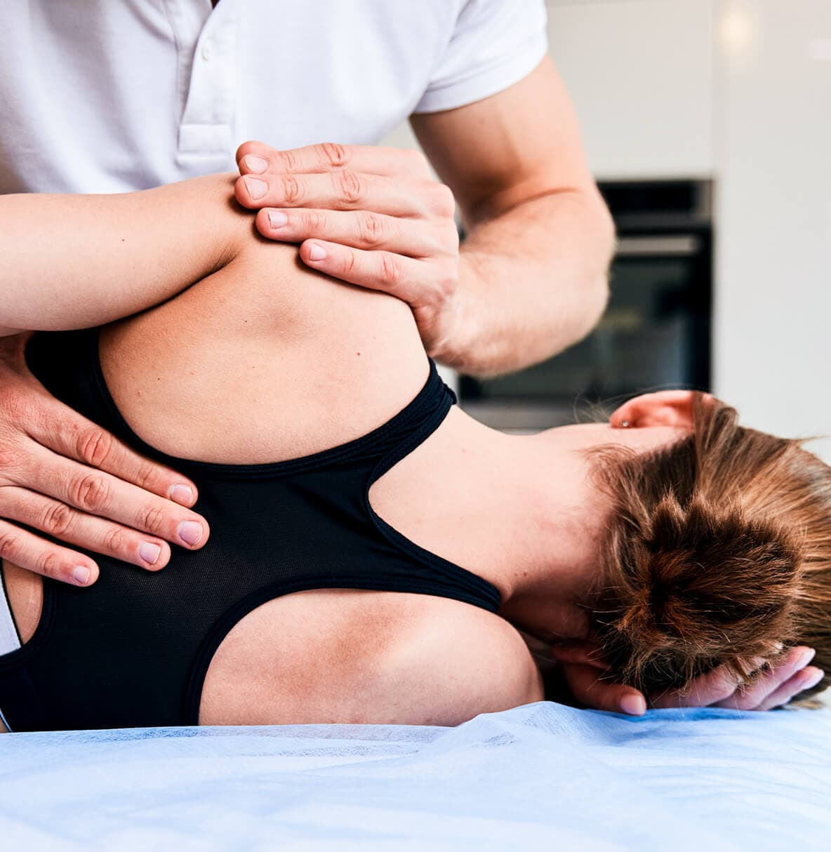 Fysiotherapeut voert een manipulatie uit op de schouder van een vrouw die op haar zij ligt.